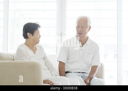 Ritratto di una seria coppia asiatica anziana che parla a casa, anziani anziani pensionati stile di vita al chiuso Foto Stock