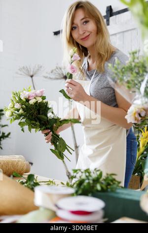 Sorridere rende fiorista bouquet nel negozio di fiori Foto Stock
