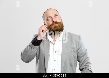 Considerato l uomo con la barba e baffi guarda fino a svuotare lo sfondo grigio Foto Stock