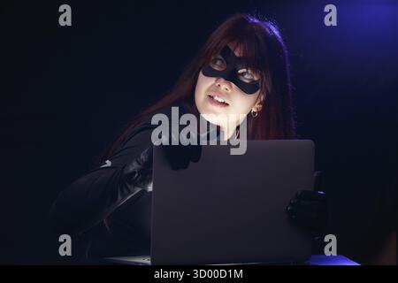 Bruna in maschera con il portatile di notte Foto Stock