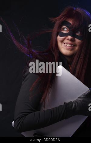 La Bruna con i capelli lunghi in maschera può contenere il computer portatile Foto Stock