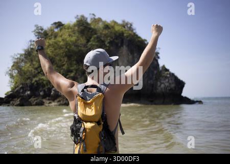 Tizio con le braccia alzate in piedi sulla costa marittima Foto Stock