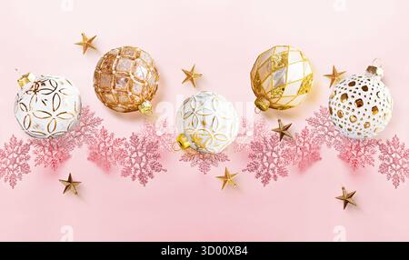 Decorazioni in oro e fiocchi di neve rosa su sfondo rosa pastello Foto Stock