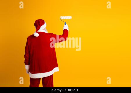 Stravagante dipinto di Babbo Natale con un rullo su sfondo giallo in allegro tema natalizio Foto Stock
