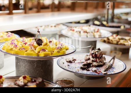 Un vivace buffet di dessert offre dolci assortiti, tra cui torte e pasticcini, splendidamente disposti su piatti d'argento pronti per essere gustati agli ospiti Foto Stock