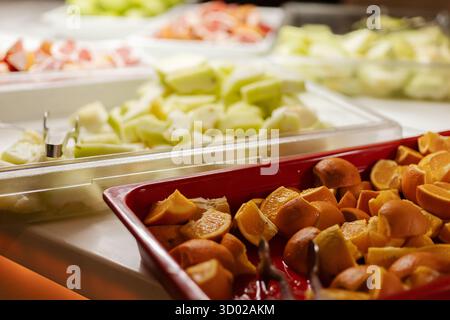 Una vivace selezione di frutta fresca è organizzata splendidamente in un buffet, con fette d'arancia, meloni e agrumi. Il display invita l'ospite Foto Stock