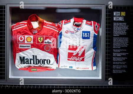 Oberhausen, Germania. 21 ottobre 2025. Le tute da corsa di Michael Schumacher e suo figlio Mick possono essere viste nella mostra. Oltre 3.000 metri quadrati di spazio all'OBEX Oberhausen Expo offriranno una panoramica del mondo delle corse. Dal 22 ottobre sarà in mostra il campione del mondo di Michael Schumacher Ferrari F1-2000. Crediti: Fabian Strauch/dpa/Alamy Live News Foto Stock