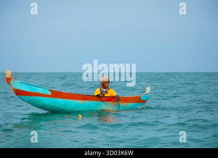 Morondava, Madagascar. 18 ottobre 2023. Il pescatore malgascio su una vecchia piroga di legno fatta in casa nell'oceano cattura il pesce con la rete. messa a fuoco selettiva, vista ravvicinata dall'oceano Foto Stock