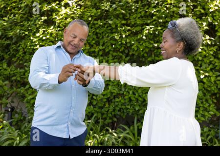 Coppia senior che si scambia anelli in giardino, festeggiando l'amore e la felicità insieme. Celebrazione, impegno, romanticismo, cerimonia, all'aperto, anziani || modello rilasciato Foto Stock