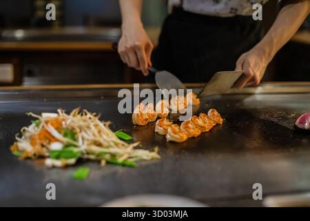 Teppanyaki, spettacolo di teppan di cucina Giapponese presso un ristorante tradizionale. mani di cuoco. Lo chef prepara carne, pesce, riso e verdure su un tavolo caldo davanti agli ospiti. cucine popoli di concetto mondiale Foto Stock