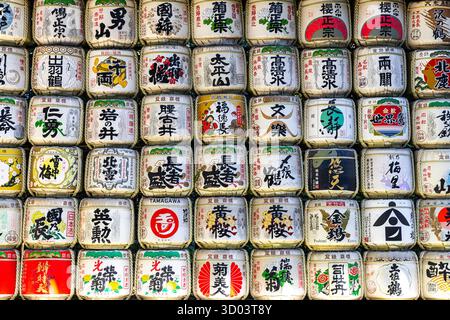 File di botti decorative di sake kazaridaru che fiancheggiano un muro in un santuario in giappone Foto Stock