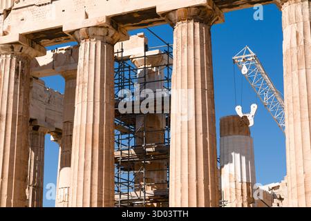 Vista ravvicinata delle colonne del partenone sull'acropoli di atene con lavori di restauro in corso, ponteggi e gru contro un cielo blu, Atene, GR Foto Stock