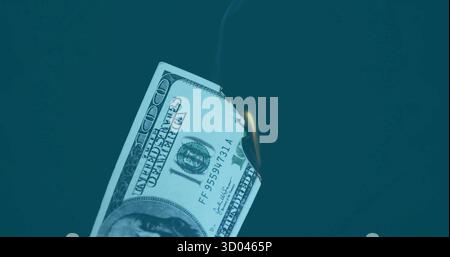 Bruciare banconote da cento dollari a destra sullo sfondo verde acqua, con fiamma e fumo Foto Stock
