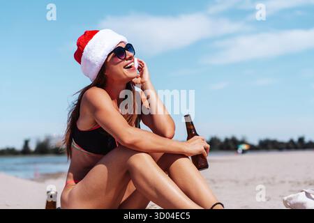 Donna moderna che festeggia il Natale su una spiaggia tropicale. Foto Stock