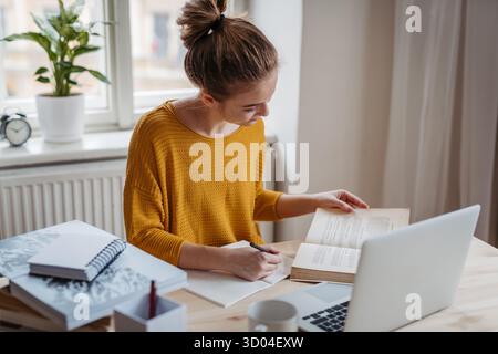 Giovane studentessa seduta a tavola e a studiare. Foto Stock