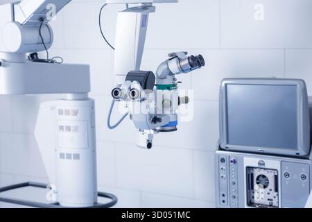 Microscopio operatorio con monitor e console in una clinica pulita pronta per microchirurgia oculare di precisione Foto Stock