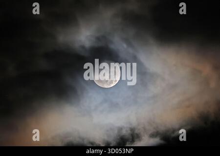 Luna piena parzialmente coperta da nuvole di notte Foto Stock
