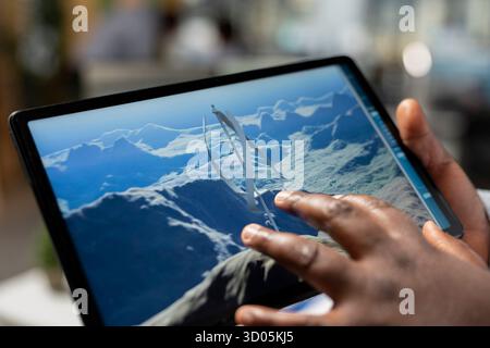 Primo piano di un tecnico che utilizza un tablet touchscreen per valutare le turbine eoliche di nuova generazione che incrementano la produzione di energia verde. Il progettista di prodotti sviluppa turbine eoliche ad asse verticale all'avanguardia utilizzando un dispositivo Foto Stock