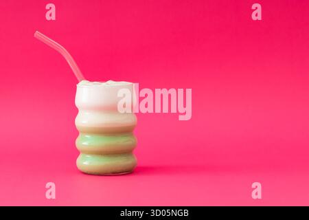 Matcha latte su sfondo rosa. Concetto minimo di latte matcha sano. Un'idea di drink alla moda. Layout a colori brillanti con spazio di copia. Foto Stock