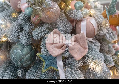 Giocattoli sull'albero di Natale e palle dorate sui rami innevati dell'albero di Natale. Sfondo natalizio. Foto Stock
