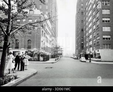 Piccolo gruppo di persone in piedi a sinistra con fotografo che fotografa una donna con cappello e vestito, vista a sud di Beekman Place all'angolo tra East 50th Street, quartiere di Turtle Bay, Manhattan, New York City, New York, New York, New York, USA, Angelo Rizzuto, Anthony Angel Collection, giugno 1958 Foto Stock