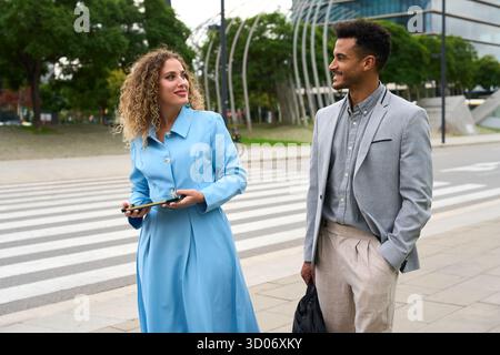 I professionisti parlano e sorridono mentre camminano per le strade della città Foto Stock