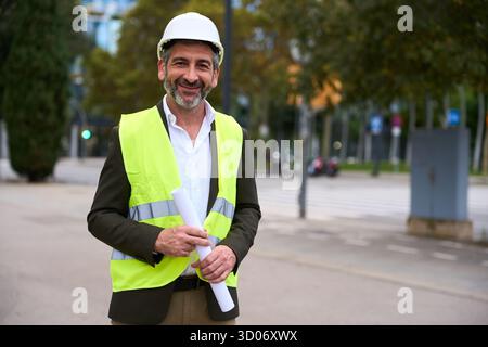 Architetto sorridente che tiene i progetti in strada urbana Foto Stock