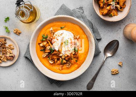 Crema di zuppa di zucca con mirtilli, noci e uovo in camicia Foto Stock