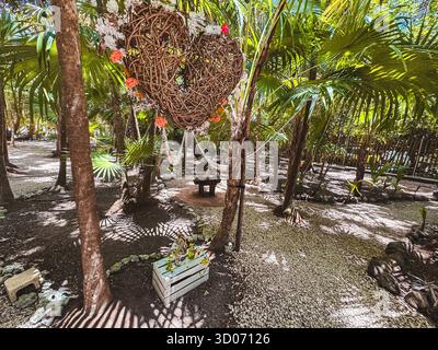 Tulum, Quintana Roo, Messico, cassa di legno con una corona a forma di cuore appesa ad essa. La corona è fatta di ramoscelli ed è appesa ad un albero. Lo scen Foto Stock