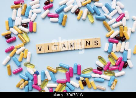 Il concetto di salute e assistenza sanitaria. Luminoso diversi tipi di farmaci per la salute. Medicinali su sfondo blu con l'iscrizione vitamine Foto Stock