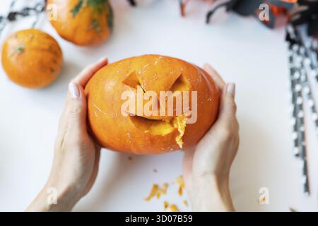 Ottobre 31. Halloween vacanza. La ragazza tiene in mano la faccia scolpita di una zucca. Vista dall'alto Foto Stock