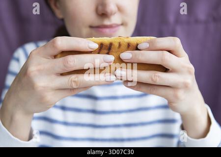 Ritratto di una bella giovane donna che sta godendo di cibo, fast food hot dog Foto Stock