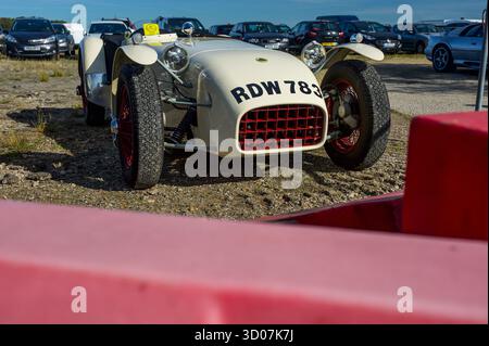 Lotus Seven Series 1 in bianco con griglia rossa, con barriere rosse in primo piano che incorniciano l'estremità anteriore Foto Stock