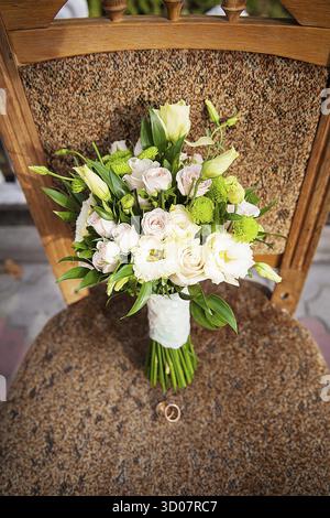 Anello e bel bouquet di fiori diversi su una sedia Foto Stock