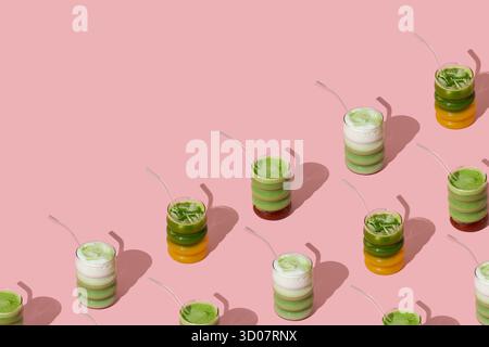 Fantasia creativa realizzata con varie bevande colorate matcha su sfondo rosa pastello con spazio copia. Concetto minimale di tè matcha sano. Foto Stock