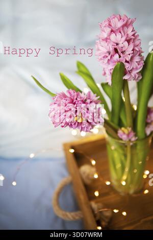 Bei giacinti rosa si ergono in un vaso su un vecchio vassoio di legno, garland, bel biglia, concetto di sorpresa. Colazione in bed, bella primavera mattina Foto Stock