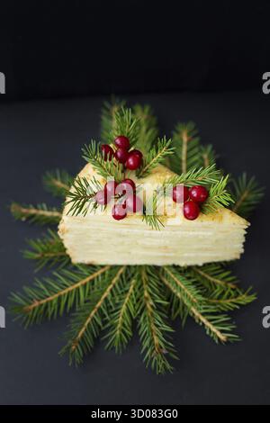 Un pezzo di torta decorato con alberi e frutti di bosco su sfondo nero Foto Stock