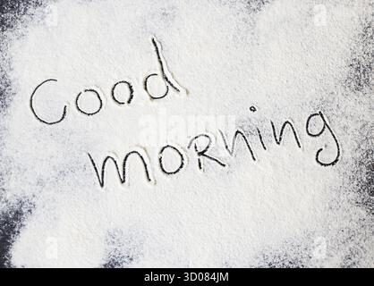 Iscrizione di buon giorno sulla tavola con farina Foto Stock