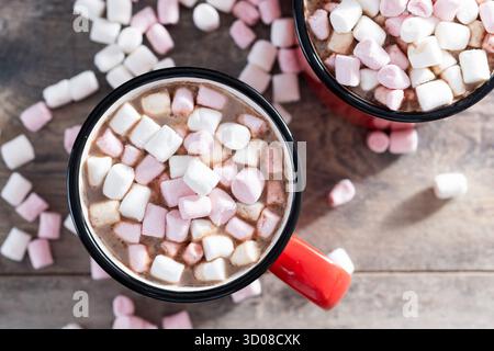 Bevanda calda a base di cioccolata con marshmallow in tazza rossa su un tavolo di legno Foto Stock