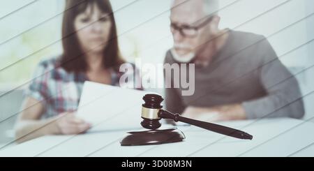 Concetto di divorzio con il gavel del giudice e la coppia leggono i documenti in background, si concentrano sul modello geometrico in primo piano Foto Stock