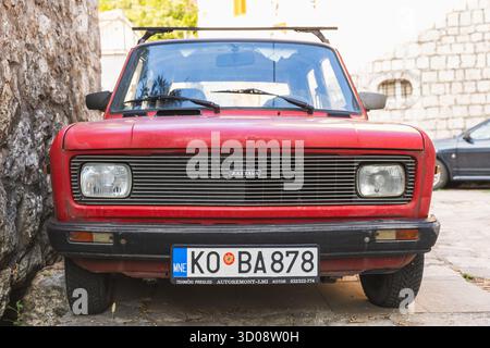 Perast, Montenegro - 11 agosto 2025: Zastava Skala 55. Vista frontale di un'auto d'epoca rossa con griglia classica e targa europea Foto Stock