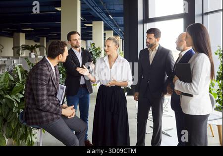 Colleghi che discutono della strategia di progetto in una moderna riunione open Office Foto Stock