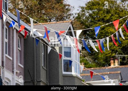 Bandiere triangolari blu, rosse e bianche di fronte alle case nella città portuale di Fowey, Cornovaglia, Inghilterra, Regno Unito, Europa Foto Stock