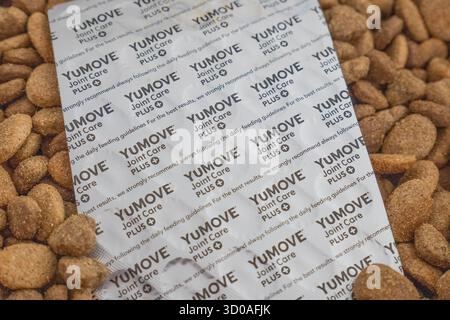 Contenitore pieno di kibble secco di cane dalle unghie e striscia di compresse YouMove insieme a una caraffa graduata Foto Stock