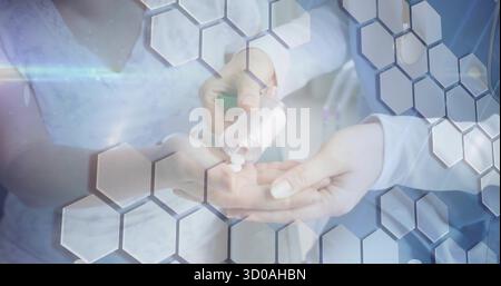 Medico che versa pillole bianche dal flacone al palmo del paziente in clinica con sovrapposizioni esagonali Foto Stock