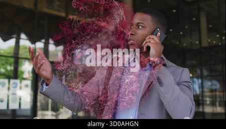 Uomo che indossa un abito con borsa, parla sullo smartphone e gesti fuori dall'ufficio con una nuvola rosso-rosa Foto Stock