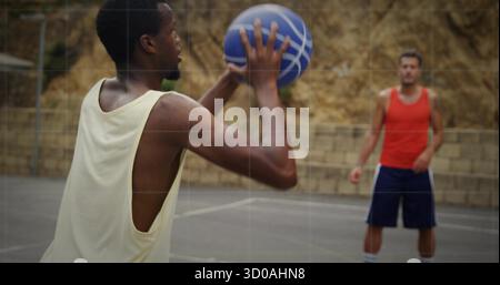 Uomo con canotta gialla che regge il basket su un campo all'aperto con parete in pietra sullo sfondo e spazio fotocopie Foto Stock