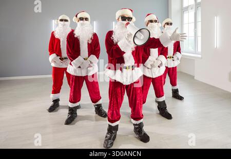 Gruppo di Santas che annuncia in ufficio, divertente ritratto della squadra per le festività aziendali Foto Stock