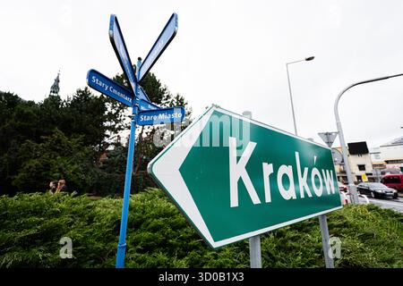 Tarnow, Polonia - 10 ottobre 2025: Segnaletica blu con direzione Cracovia in mezzo al verde e ai dintorni urbani di Tarnow, Polonia. Foto Stock