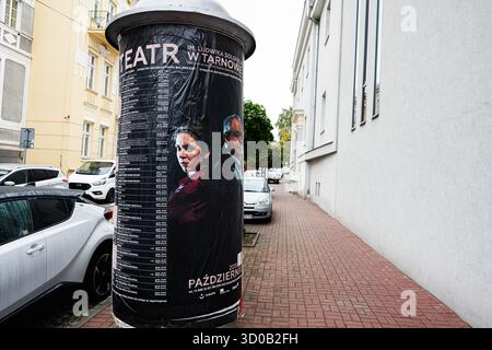 Tarnow, Polonia - 10 ottobre 2025: Poster promozionale che copre una colonna stradale a Tarnow, Polonia, vicino alle auto parcheggiate e agli edifici pallidi. Foto Stock